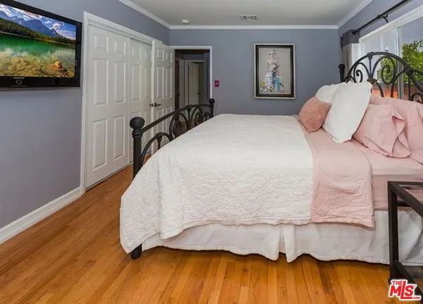 a bedroom with a bed and a potted plant on the dresser