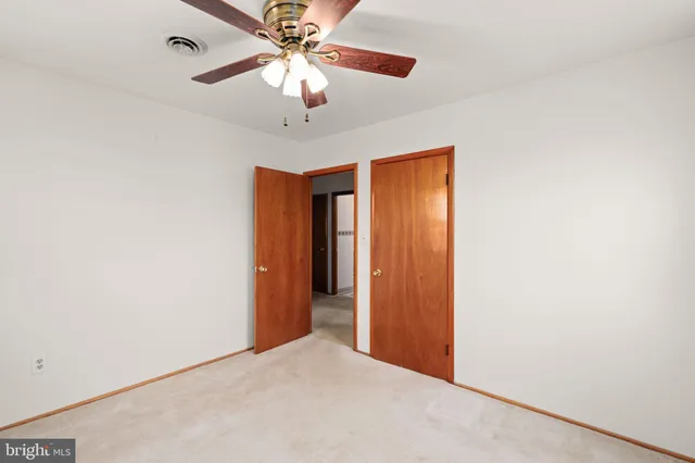 an empty room with a chandelier fan and closet
