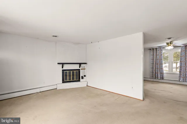 an empty room with chandelier fan and windows