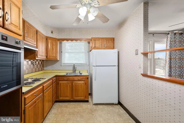 a kitchen with stainless steel appliances granite countertop a refrigerator a sink dishwasher a stove with white cabinets and wooden floor