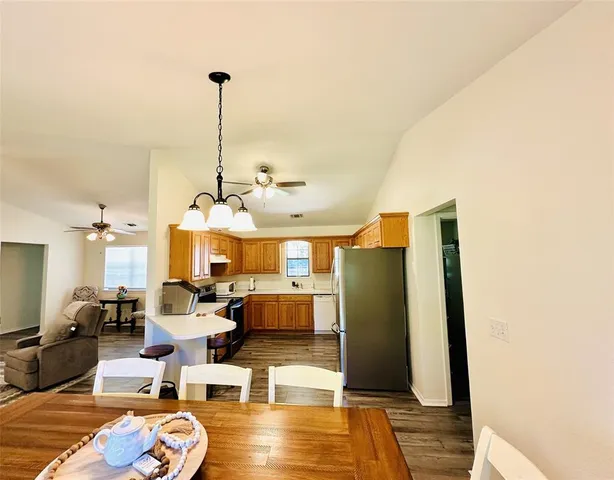 a living room with couches a fireplace and kitchen view with wooden floor