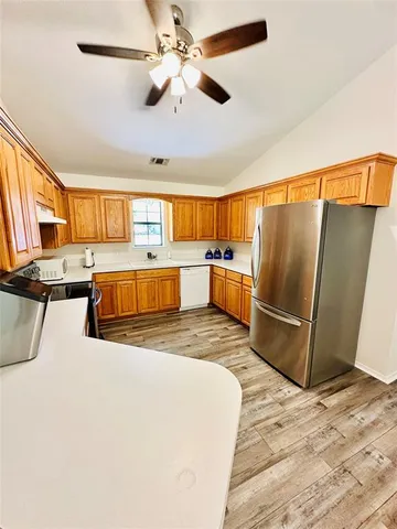 a kitchen with stainless steel appliances granite countertop a refrigerator a stove and a sink with cabinets