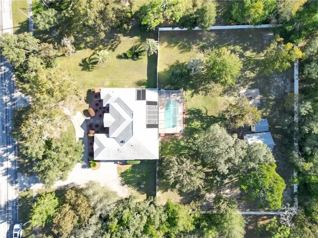 an aerial view of residential houses with outdoor space and trees all around
