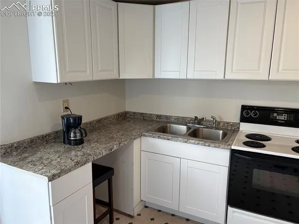 a kitchen with white cabinets and sink