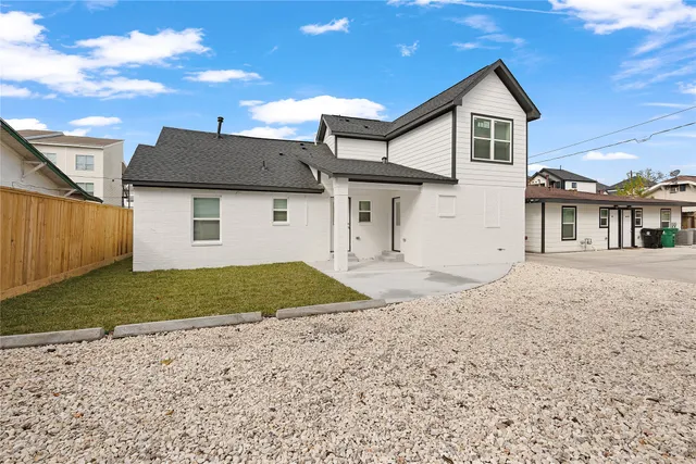 a view of a white house next to a yard and a large tree