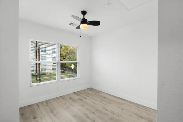 an empty room with a window and a ceiling fan