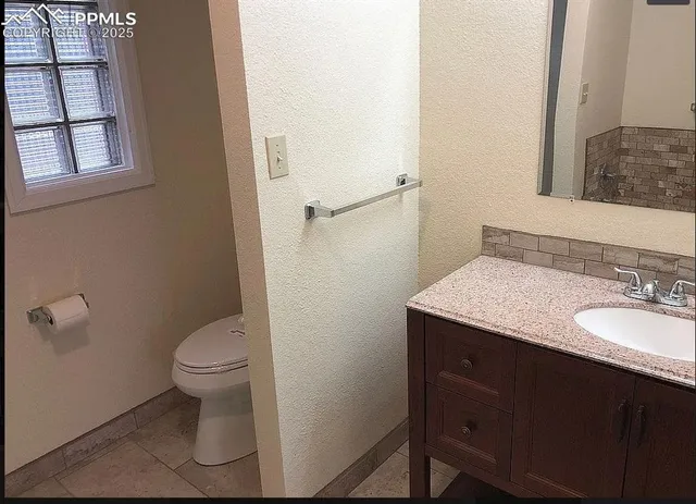 a bathroom with a granite countertop sink toilet and mirror