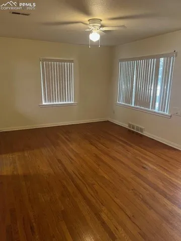 a view of an empty room with wooden floor and a window