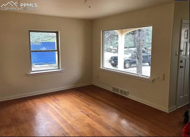 a view of an empty room with wooden floor and a window