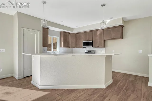 a view of a kitchen with wooden floor and electronic appliances