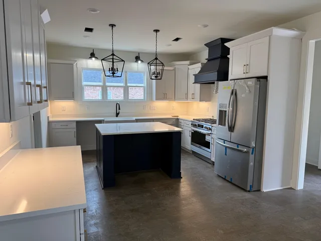 a kitchen with stainless steel appliances granite countertop a refrigerator a sink a stove and a refrigerator