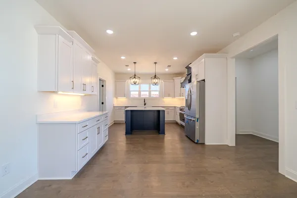 a view of an empty room and a kitchen with a sink windows