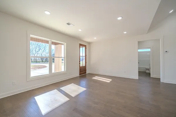 an empty room with windows and ceiling fan