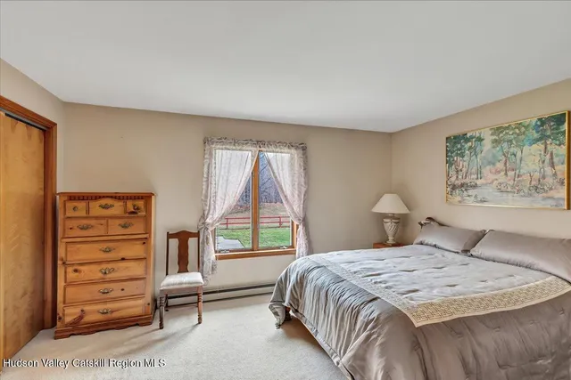 a bedroom with a bed a dresser and a large window