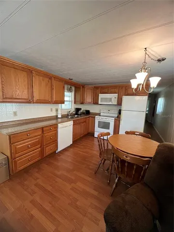 a open kitchen with stainless steel appliances granite countertop a stove a sink dishwasher and a dining table with wooden cabinet