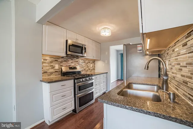 a kitchen with granite countertop a sink stove and microwave