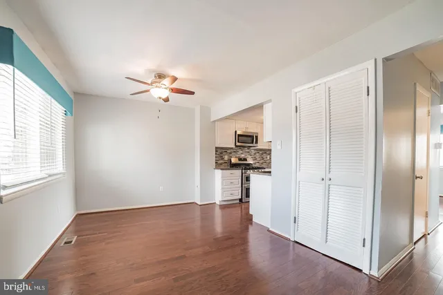 a view of a kitchen with a sink a refrigerator a ceiling fan and wooden floor