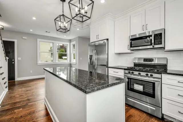 a kitchen with stainless steel appliances granite countertop a stove a microwave and a refrigerator