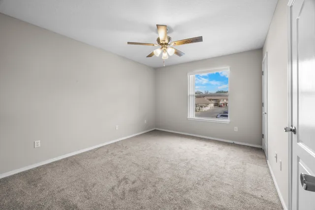 an empty room with windows and fan