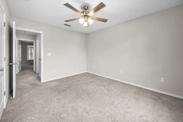 an empty room with a chandelier fan and windows