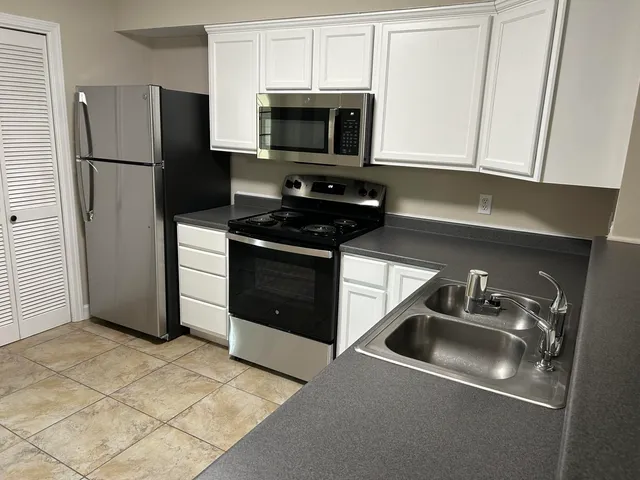 a kitchen with stainless steel appliances a refrigerator a sink a stove a microwave and cabinets