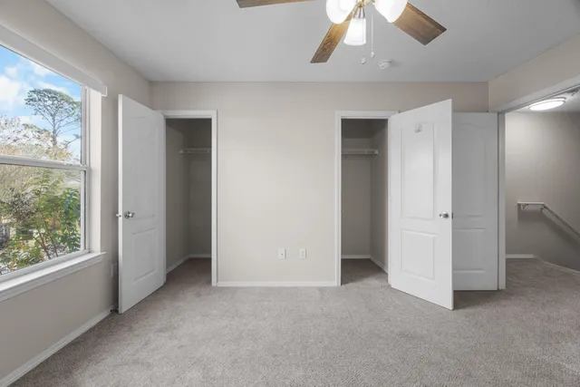 an empty room with chandelier fan and windows