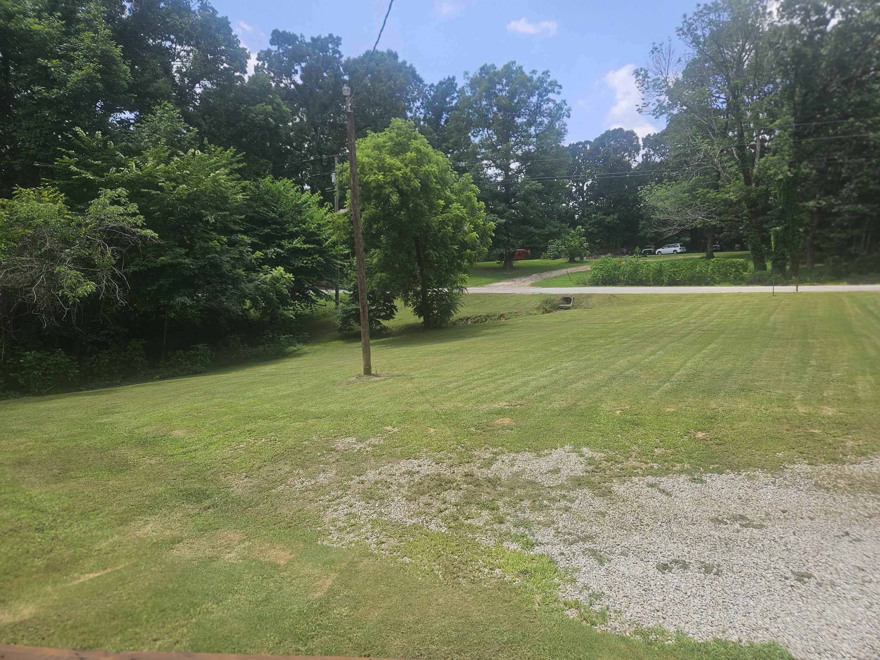 75 Pittman Road, Unit ROAD Somerville, TN 38068 - Photo 25 of 26 Expansive outdoor space featuring a large grassy lawn, gravel area, and mature trees bordering the property