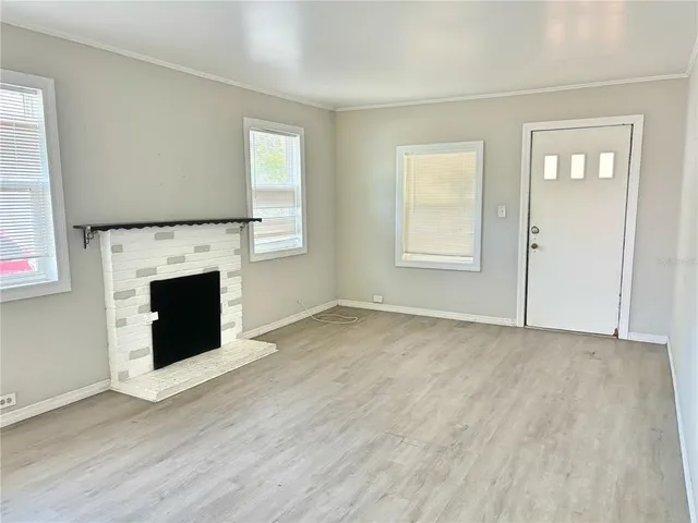 an empty room with windows and fireplace