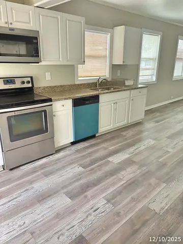 a kitchen with stainless steel appliances granite countertop a stove a sink and a microwave