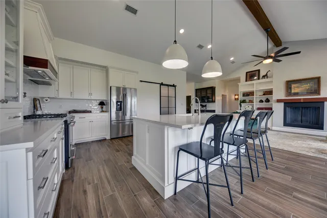 a kitchen with stainless steel appliances kitchen island granite countertop a table chairs microwave and cabinets