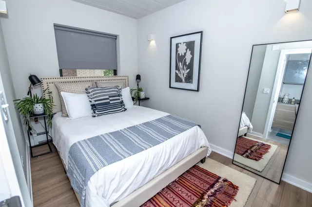 a bedroom with a bed wooden floor and a flat screen tv