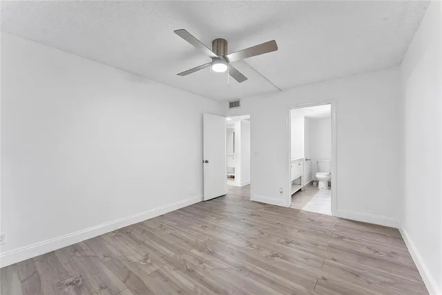 an empty room with wooden floor and a ceiling fan