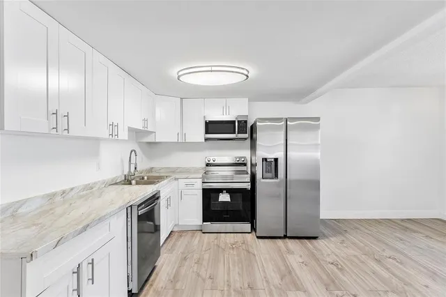 a kitchen with stainless steel appliances granite countertop a stove a sink and a refrigerator