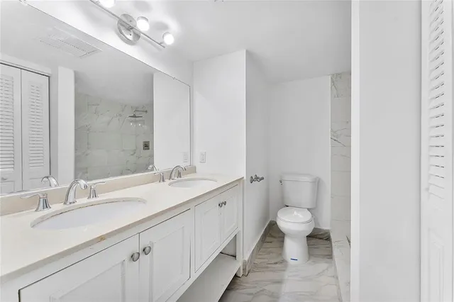 a bathroom with a double vanity sink toilet and a mirror