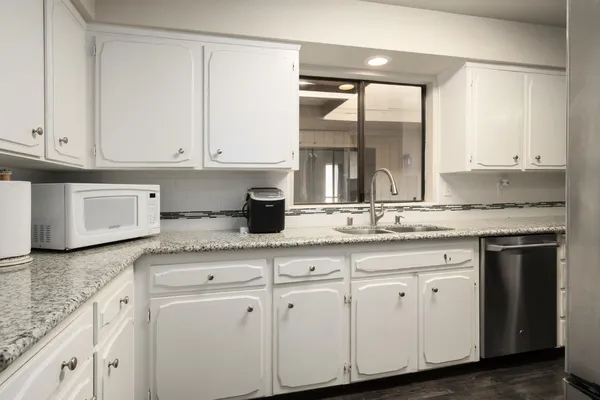 a kitchen with granite countertop white cabinets and a sink