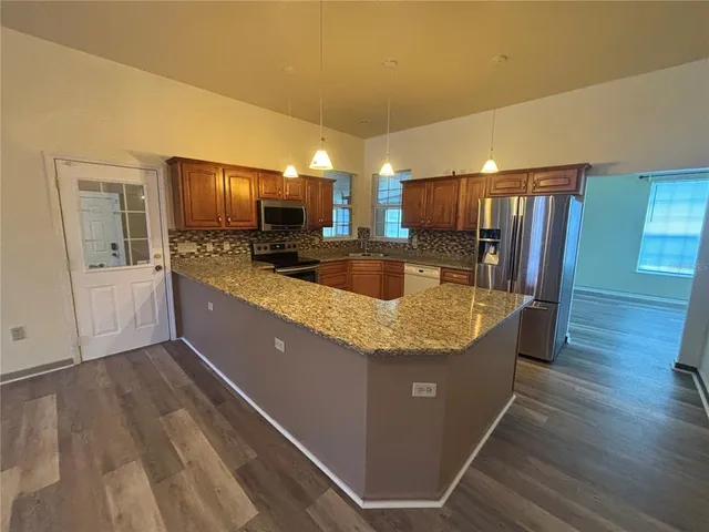 a kitchen with stainless steel appliances granite countertop a sink a stove and a refrigerator