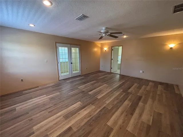 an empty room with wooden floor and windows