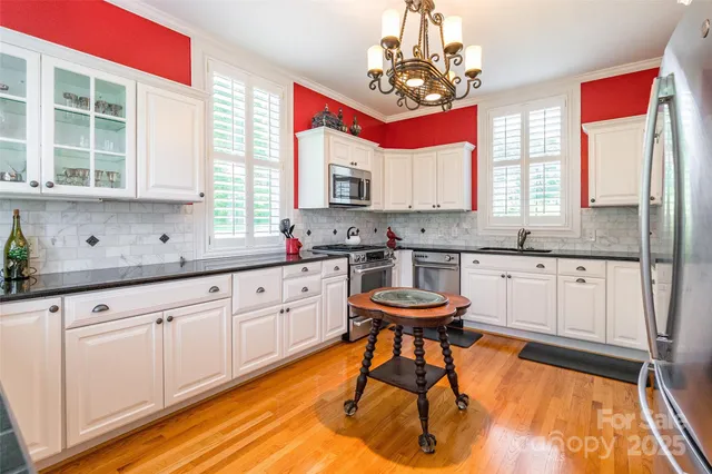 a kitchen with stainless steel appliances granite countertop white cabinets a sink and dishwasher with wooden floor