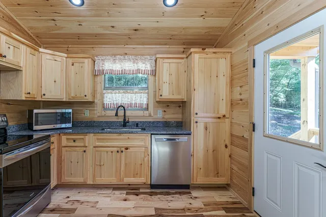a kitchen with stainless steel appliances granite countertop a sink window and cabinets