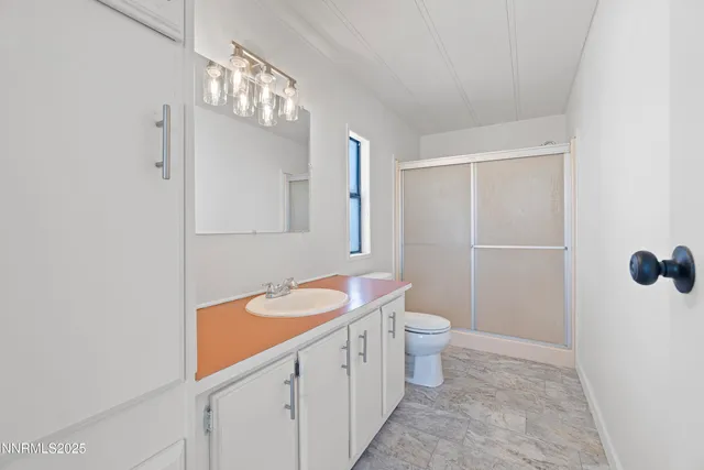 a bathroom with a sink a toilet a mirror and shower