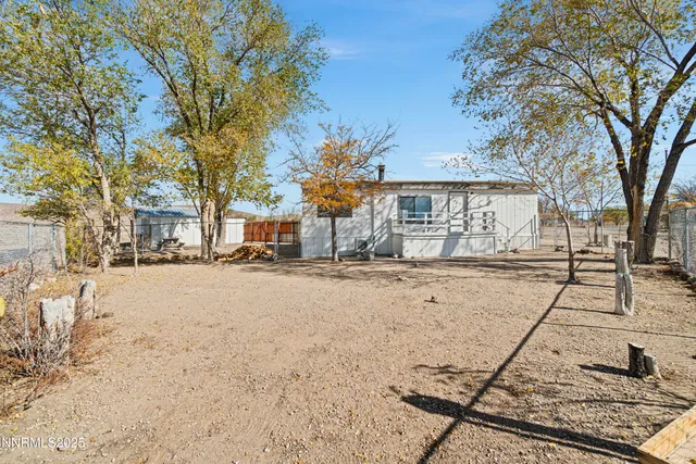 a view of backyard with large trees and wooden fence