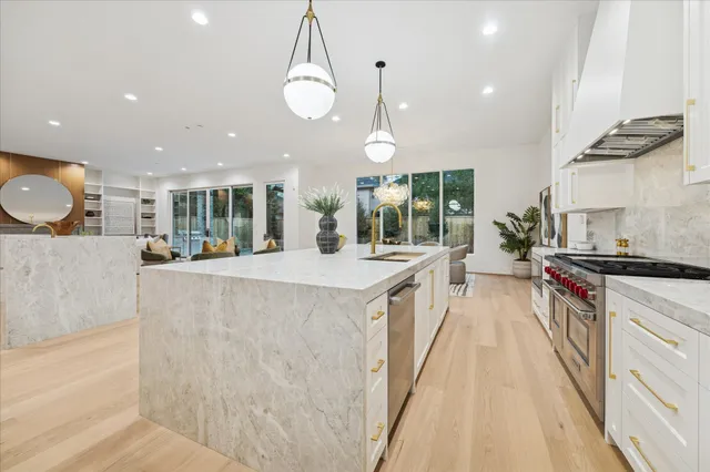 a large kitchen with stainless steel appliances a large counter top a stove and a sink