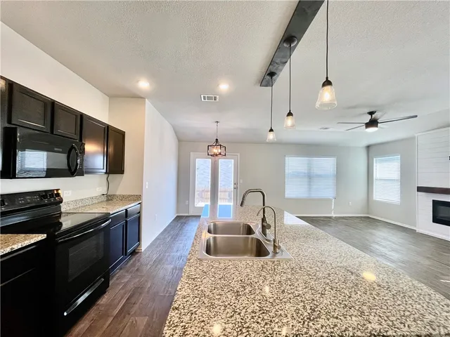 a kitchen with stainless steel appliances granite countertop a sink stove and refrigerator