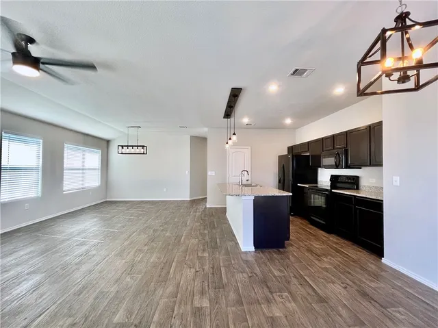 a large living room with stainless steel appliances kitchen island granite countertop a large counter top and view of living room