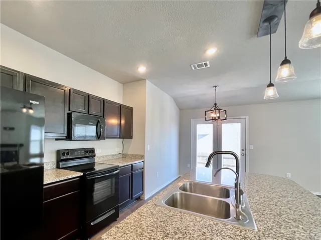 a kitchen with stainless steel appliances kitchen island granite countertop a stove a sink and a refrigerator
