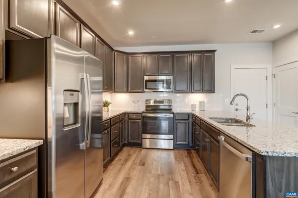 a kitchen with stainless steel appliances granite countertop a sink a stove a dining table and chairs