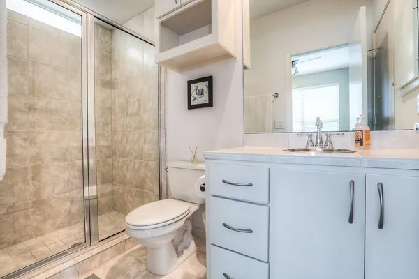 a bathroom with a toilet a sink a mirror and shower