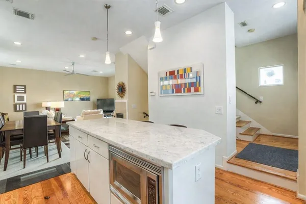 a open kitchen with kitchen island a stove a sink a dining table and chairs with wooden floor