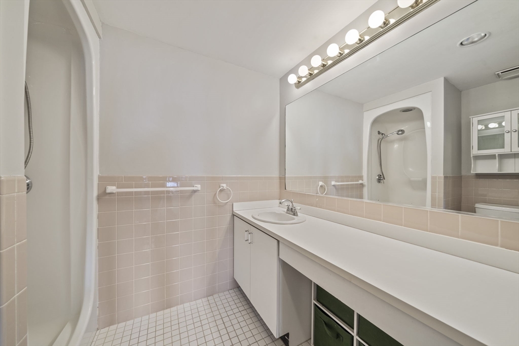 155 George Washington Boulevard, Unit 402 Hull, MA 02045 - Photo 16 of 42 a bathroom with a sink a large mirror and a shower