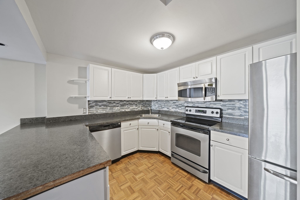 155 George Washington Boulevard, Unit 402 Hull, MA 02045 - Photo 4 of 42 a kitchen with stainless steel appliances granite countertop a stove a sink and a refrigerator